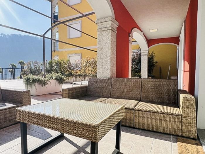 Eine ca. 100 m² große, teils überdachte Terrasse mit herrlichem Panoramablick auf den See, die umliegenden Berge und den gepflegten Palmengarten